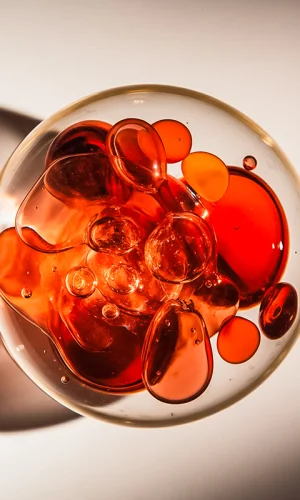 Nærbillede af bobler og væsker i glas – kunstnerisk makrofotografi med røde nuancer